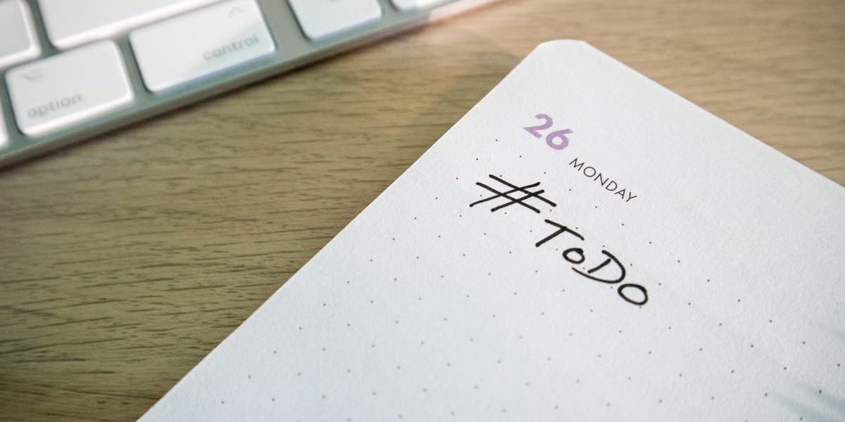 Close-up of a to-do list next to a computer keyboard on a desk.