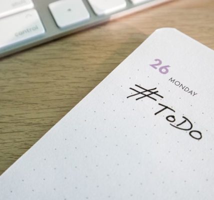 Close-up of a to-do list next to a computer keyboard on a desk.
