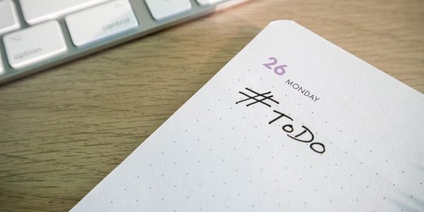Close-up of a to-do list next to a computer keyboard on a desk.